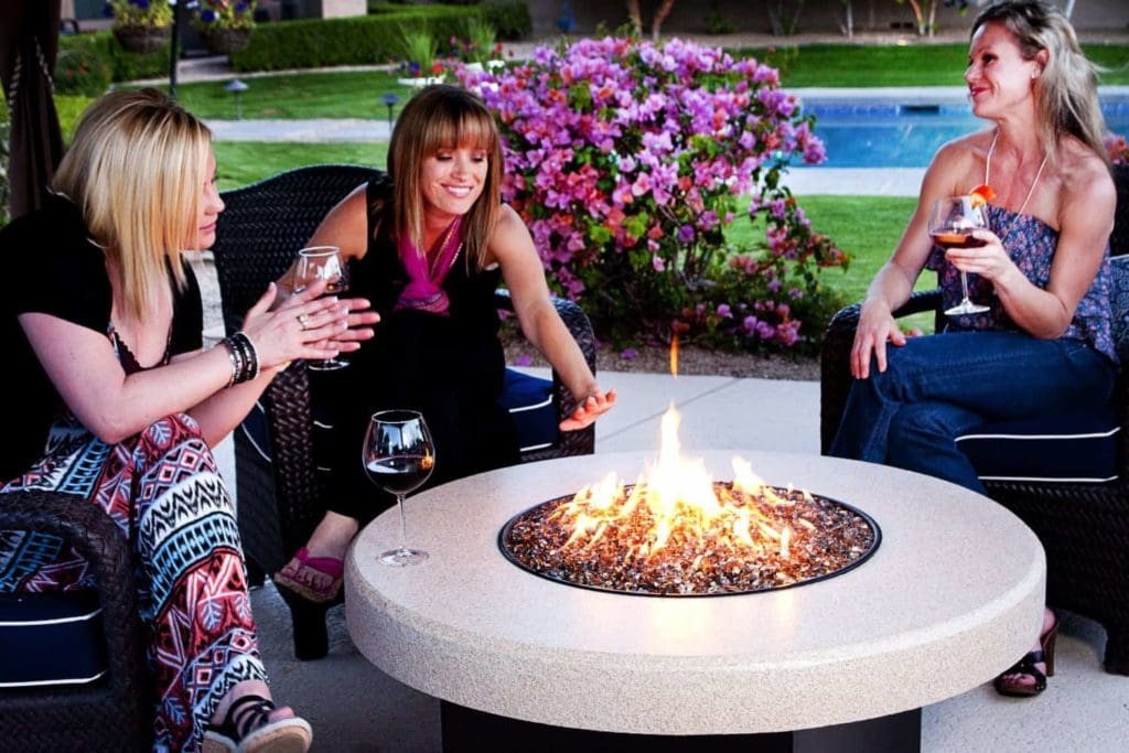 women sit around outdoor gas fireplace