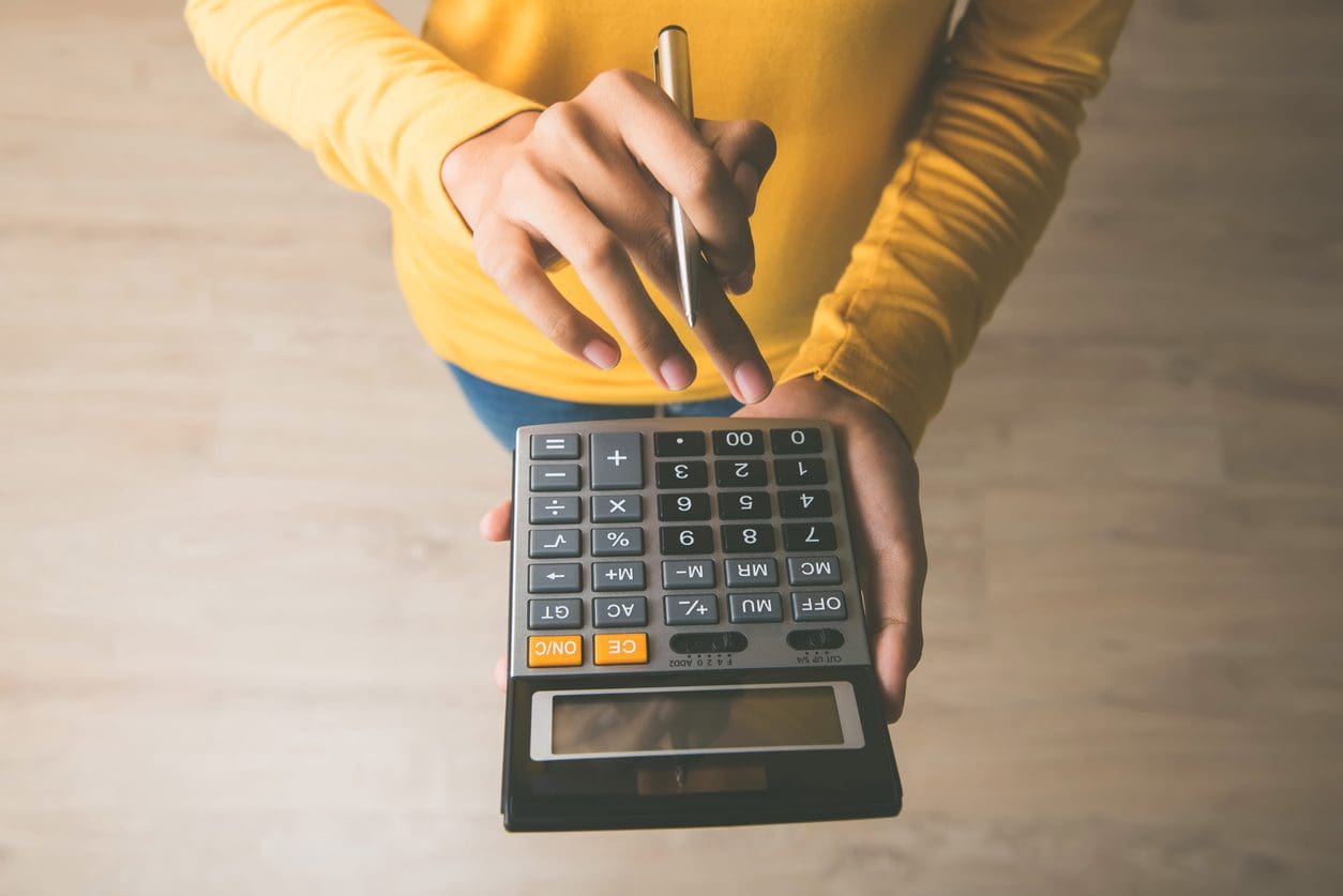 Woman using a calculator to weigh the costs of repair versus replacement.